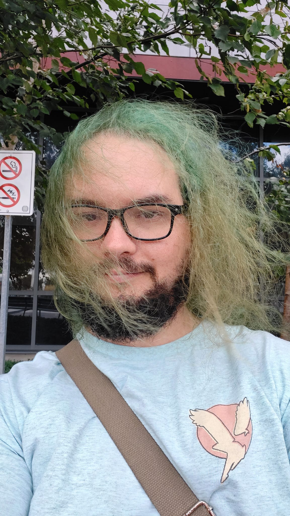 A man with green hair and a beard is in street clothes outside the hospital, Photo 1